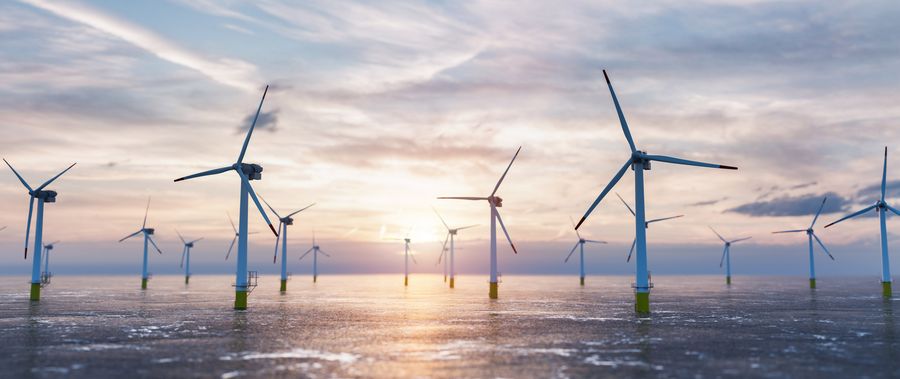© Dreamstime.com. Offshore wind power and energy farm with wind turbines on the ocean.